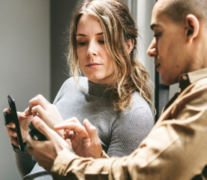 man and woman holding smartphones